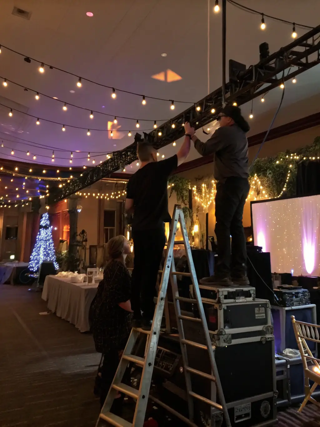 A team of event coordinators setting up stage equipment and managing event logistics in a community hall.